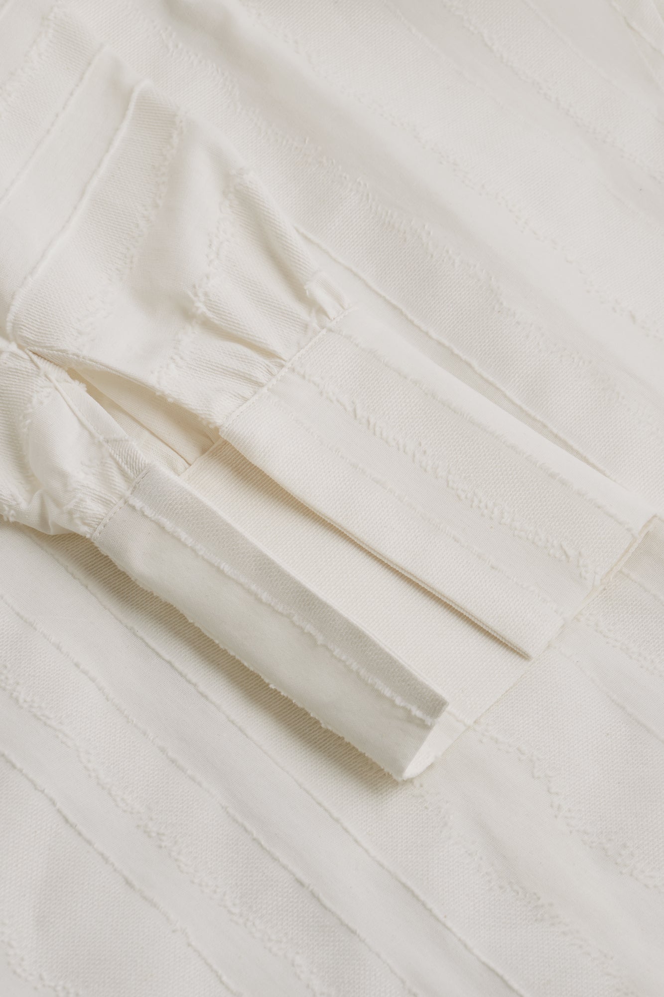 Close-up of a white fabric with a subtle pattern on a light wooden surface